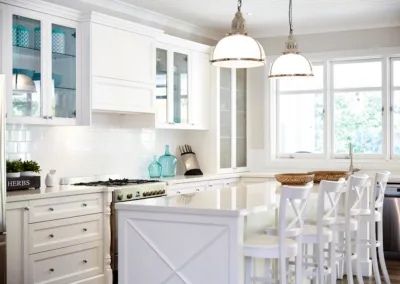 A kitchen with white cabinets and stools.